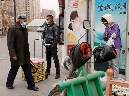 Residentes con mascarillas pasean por la ciudad de Aksu, en Xinjiang, región china donde vive la mayoría de la comunidad uigur.