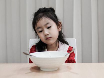 Una niña mira la comida sin hambre. 