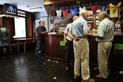 Tres hombres toman algo en un bar de Hernani (Guipúzcoa) sin hacer caso al comunicado de ETA que se emite en televisión