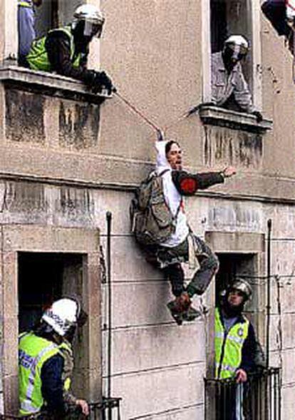 Agentes de la Guardia Urbana descuelgan a uno de los seis okupasde la fachada del edificio de la plazoleta del Pi.