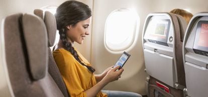 Una pasajera consulta su tableta en un vuelo intercontinental de Iberia.