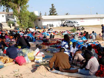 Los migrantes, con sus pertenencias, en el exterior del centro de detención bombardeado en Trípoli.