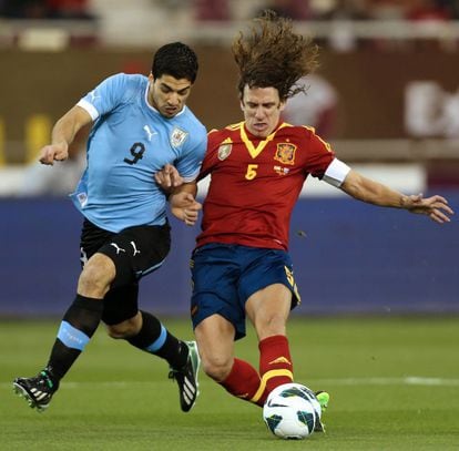 Carles Puyol pelea el balón con Luis Suarez.