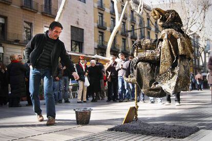 Turistas contemplando una de las estatuas más admiradas de La Rambla de Barcelona.