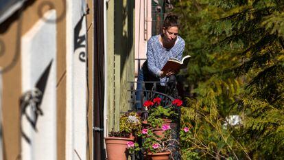 Una mujer lee un libro en el balcón de su casa, durante el confinamiento en Barcelona.