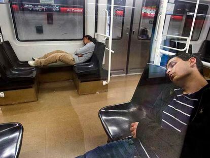 Dos jóvenes duermen en los vagones del metro de Barcelona a primeras horas de la mañana.