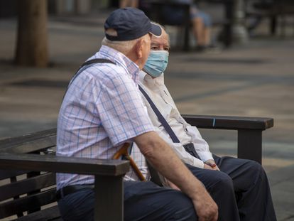 Dos hombres, uno protegido con mascarilla, charlan sentados en un banco este miércoles en Vitoria (España).