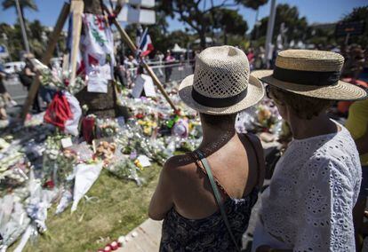 Varios turistas, ante los ramos de flores colocados en el lugar del atentado de Niza. 