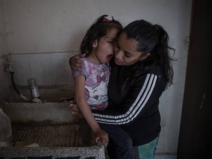 Valeria González y su hija Liz, que sufre discapacidad múltiple, en el lavadero donde se asean. Viven sin agua corriente en Ecatepec (México).