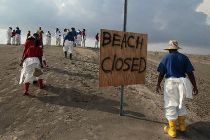 Trabajadores se dirigen a limpiar una playa cerrada en Grand Isle, Luisiana.