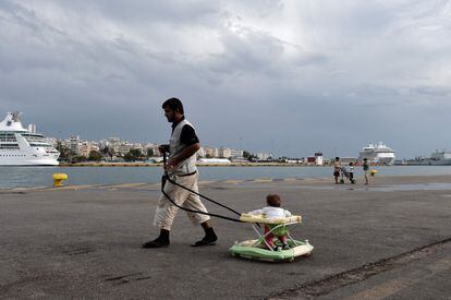 Un hombre arrastra a su bebé en un andador en el puerto de El Pireo, en Atenas.