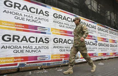Un uniformado pasa frente a los carteles de agradecimiento del candidato presidencial Mauricio Macri que aparecieron este lunes en Buenos Aires.