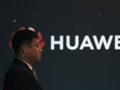 Logo de Huawei en un stand de la compa&ntilde;&iacute;a junto a una persona de seguridad. 