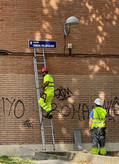 Dos operarios colocan el nuevo rótulo de la calle General Millán Astray en el callejero de Madrid.