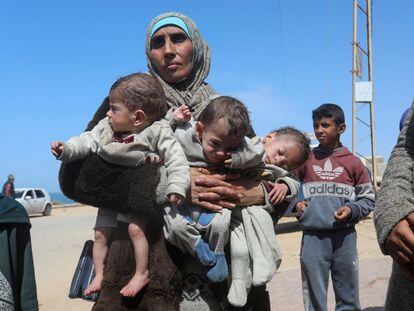 Una mujer palestina con tres niños en brazos abandonaba este jueves el hospital Al Shifa, asediado por el ejército israelí, en Gaza.