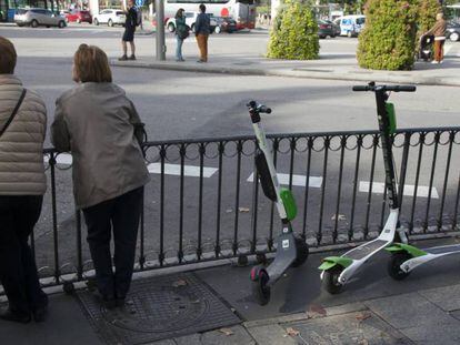 Dos mujeres apoyadas junto a unos patinetes aparcados. En vídeo, cada ayuntamiento tiene su propia normativa sobre el uso del patinete eléctrico.