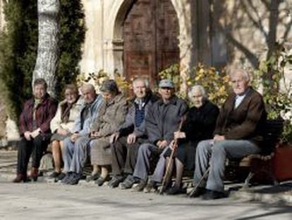 Varios ancianos toman el sol en unos bancos de Olmeda de la Cuesta, Cuenca. 