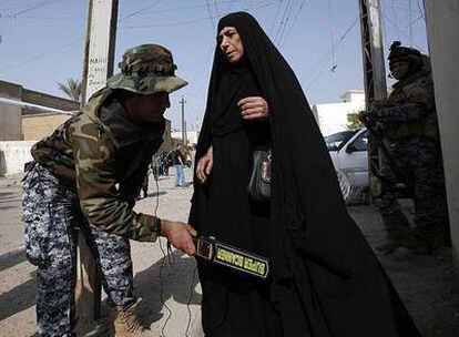 Un policía iraquí pasa un escáner a una mujer en un puesto de control ante un colegio electoral el sábado.
