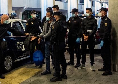 Dos jóvenes migrantes marroquíes esposados llegan al aeropuerto de Las Palmas, Canarias para ser deportados por la policía, en diciembre 2020.