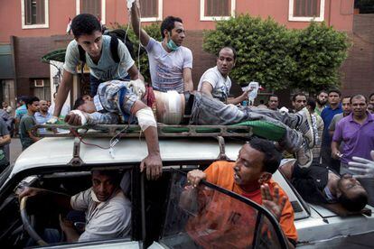 Dos heridos en los enfrentamientos de El Cairo son evacuados en la baca y el port&oacute;n del maletero de un coche a modo de ambulancia improvisada. 