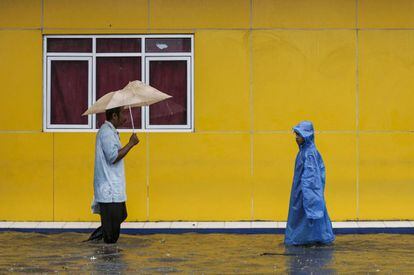 Varios residentes de la ciudad de Yakarta (Indonesia) caminan por las aguas que han dejado las inundaciones. La ciudad fue golpeada por las inundaciones generalizadas este martes después de horas de lluvias torrenciales dejando miles de hogares inundados, coches varados y personas forzadas a caminar a través del agua cenagosa.