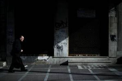 Un hombre camina frente a varios comercios cerraos en Atenas, Grecia, hoy. El gobierno griego ha ofertado a los inversores privados recomprar parte de su propia deuda a un precio que se situaría entre un 30 y un 40 % de su valor nominal.