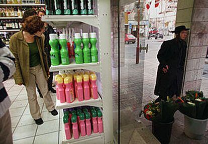 Una mujer israelí mira artículos en un supermercado. Fuera de la tienda, un judío ultraortodoxo.