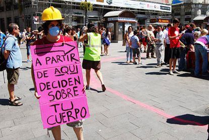 Una chica, con un cartel, señala la zona en la que se ha instalado una caseta desde la que se reparte información en contra del aborto.