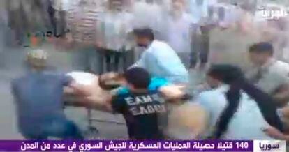 El canal de televisión Al Arabiya ofrece una imagen de varios manifestantes sirios que evacúan a un hombre herido tras la operación del Ejército sirio en la ciudad de Hama