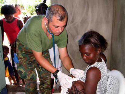 El capitán médico del Ejército español Juan Plaza atiende a una niña en la localidad haitiana de Fort Liberté.