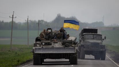 Un carro con una bandera de Ucraina junto a un camion lanzacohetes circulan por una carretera cercana a Lissitxansk.