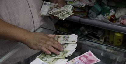 Un dependiente cuenta billetes de yuanes en una tienda de Pekín, China. 