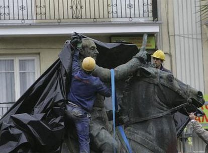 Tres operarios trabajan en la retirada de la estatua de Franco de Santander.