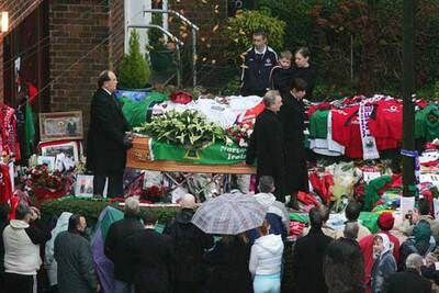 El féretro de George Best es sacado de su casa en Belfast, a la izquierda, rodeado de admiradores.