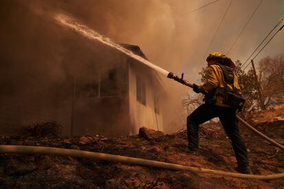 En menos de tres días, las llamas ya han consumido más de 970 hectáreas y se han cobrado la vida de dos personas. En la imagen, un bombero intenta sofocar el fuego que consume una vivienda en Hemet, el 6 de septiembre de 2022.  