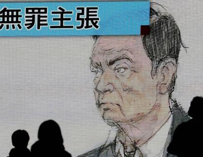 Peatones caminan junto a una pantalla en la que aparece un retrato del expresidente de Nissan Carlos Ghosn.