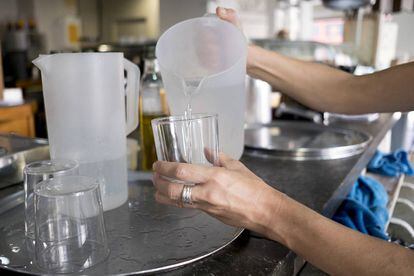 Una mujer echa agua en un vaso en un bar de Sevilla.