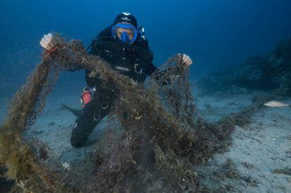 Un buzo que explora los fondos marinos muestra una red de pesca abandonada que acaba de encontrar en Marsella (Francia) en agosto de 2017.
