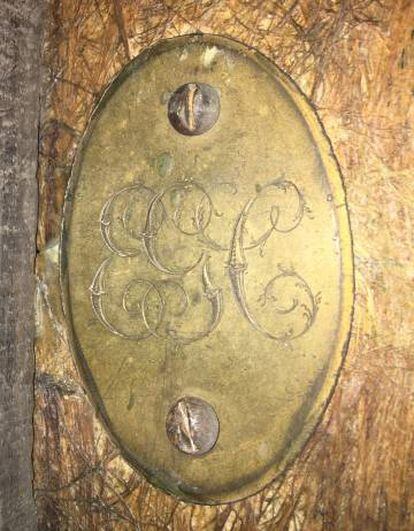 La placa cargolada amb les tres inicials que es va col·locar a la part posterior de la taula.