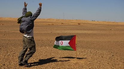 Un activista del Frente Polisario trata de llamar la atención de los soldados marroquíes, apenas perceptibles, como puntos negros, detrás del muro construido por Rabat en el Sáhara, al fondo.