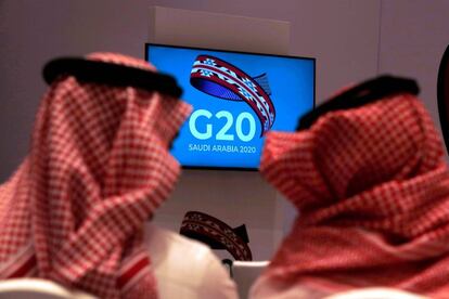 Dos funcionarios saudíes siguen en un televisor la reunión de ministros de Finanzas y gobernadores de los bancos centrales del G20 en Riad.