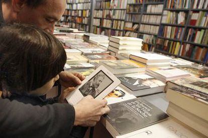 Usuarios de Kindle, <i>e-book</i> de Amazon, leen un libro electrónico en una librería de Madrid.