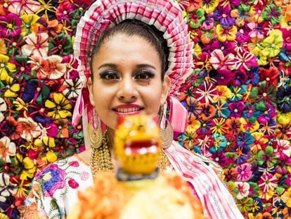 Una joven enmarcada por flores artesanales confeccionadas con hojas de maíz en el estand de México en la Feria Internacional de Turismo de Madrid (Fitur).