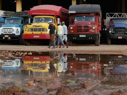 Un grupo de trabajadores pasan ante unos camiones, en La Habana.