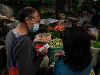 Una pareja compra verduras en un mercado en Bogotá.