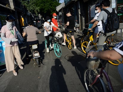 Una trabajadora social comprueba la temperatura de varias personas en una calle de Pekín.