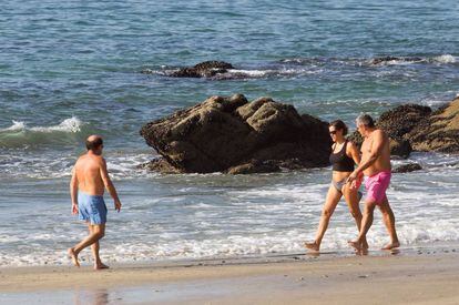 Varias personas pasean este jueves de otoño por la playa de Samil.