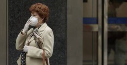 Una mujer camina con una mascarilla FFP2.