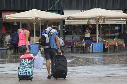 Unos turistas caminan con sus maletas por el barrio de La Barceloneta.