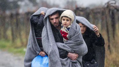 Una família camina aquest divendres sota la pluja a la frontera entre Grècia i Macedònia.